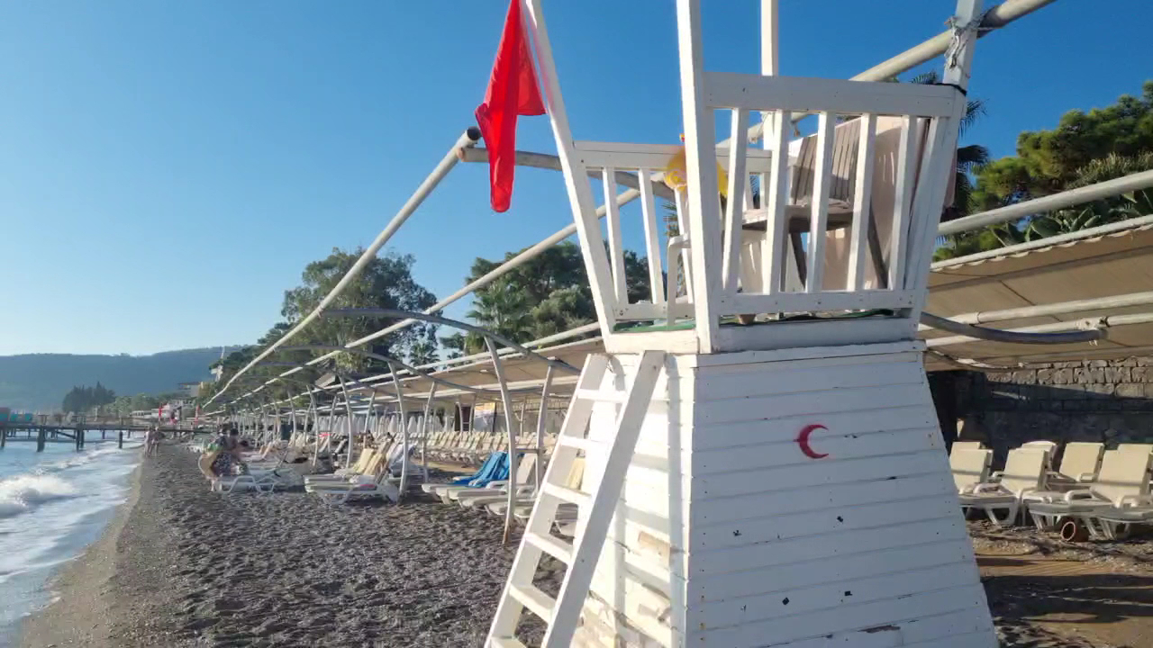Crystal Aura Beach Resort & Spa pludmales glābēju tornis un sauļošanās krēsli pie jūras krasta saulainā dienā