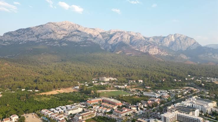 Crystal Aura Beach Resort & Spa panorāmas skats no putna lidojuma Kemeras reģionā — viesnīcas komplekss pie Taurus kalnu pakājes