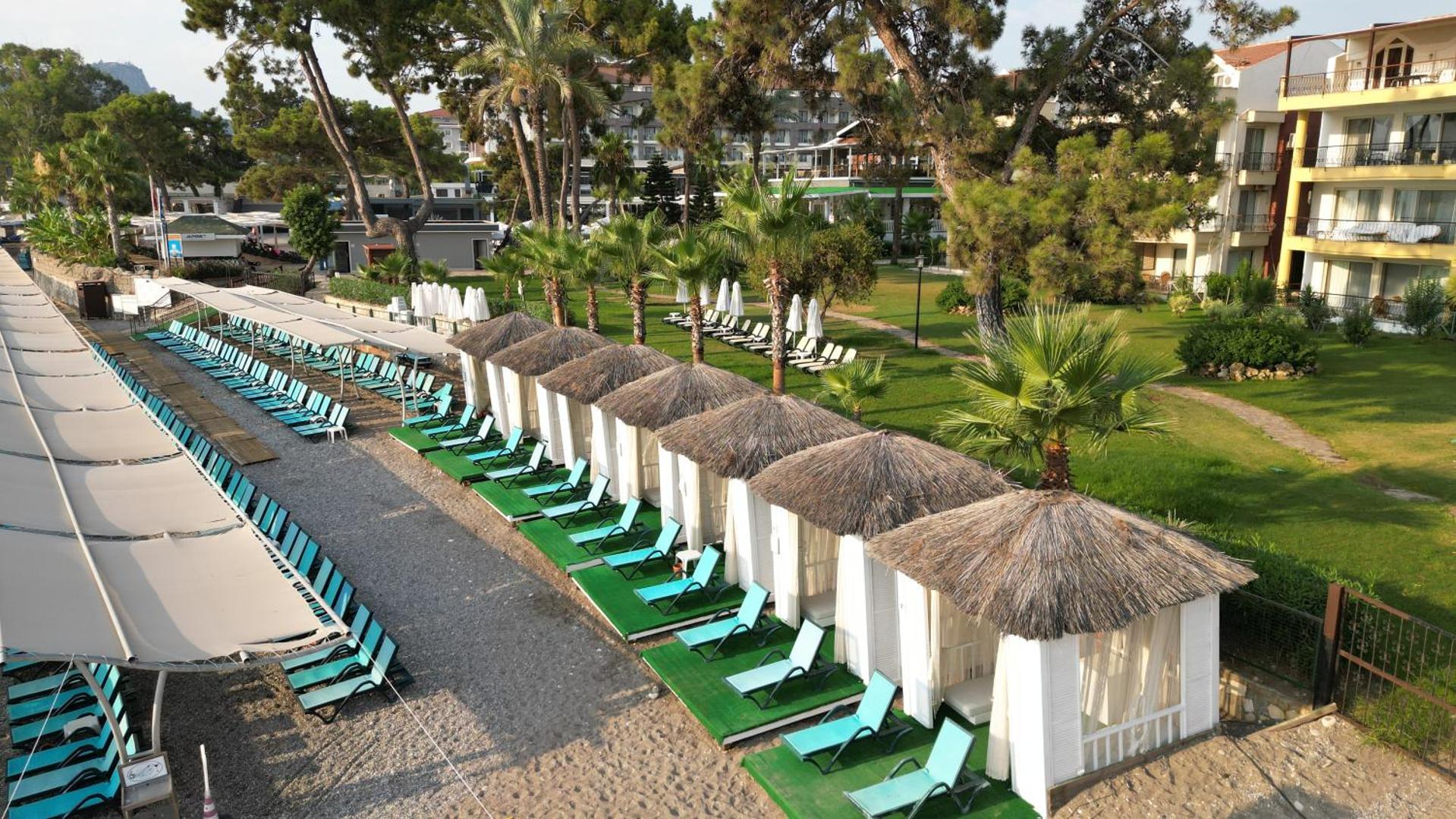 Crystal Aura Beach Resort & Spa pludmales nojumes jeb bungalo ar salmu jumtiem un ziliem sauļošanās krēsliem zālienā