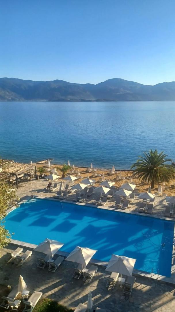 Skats no augšas uz Long Beach Resort baseinu, pludmali ar saulessargiem un zilo jūru ar kalniem tālumā.