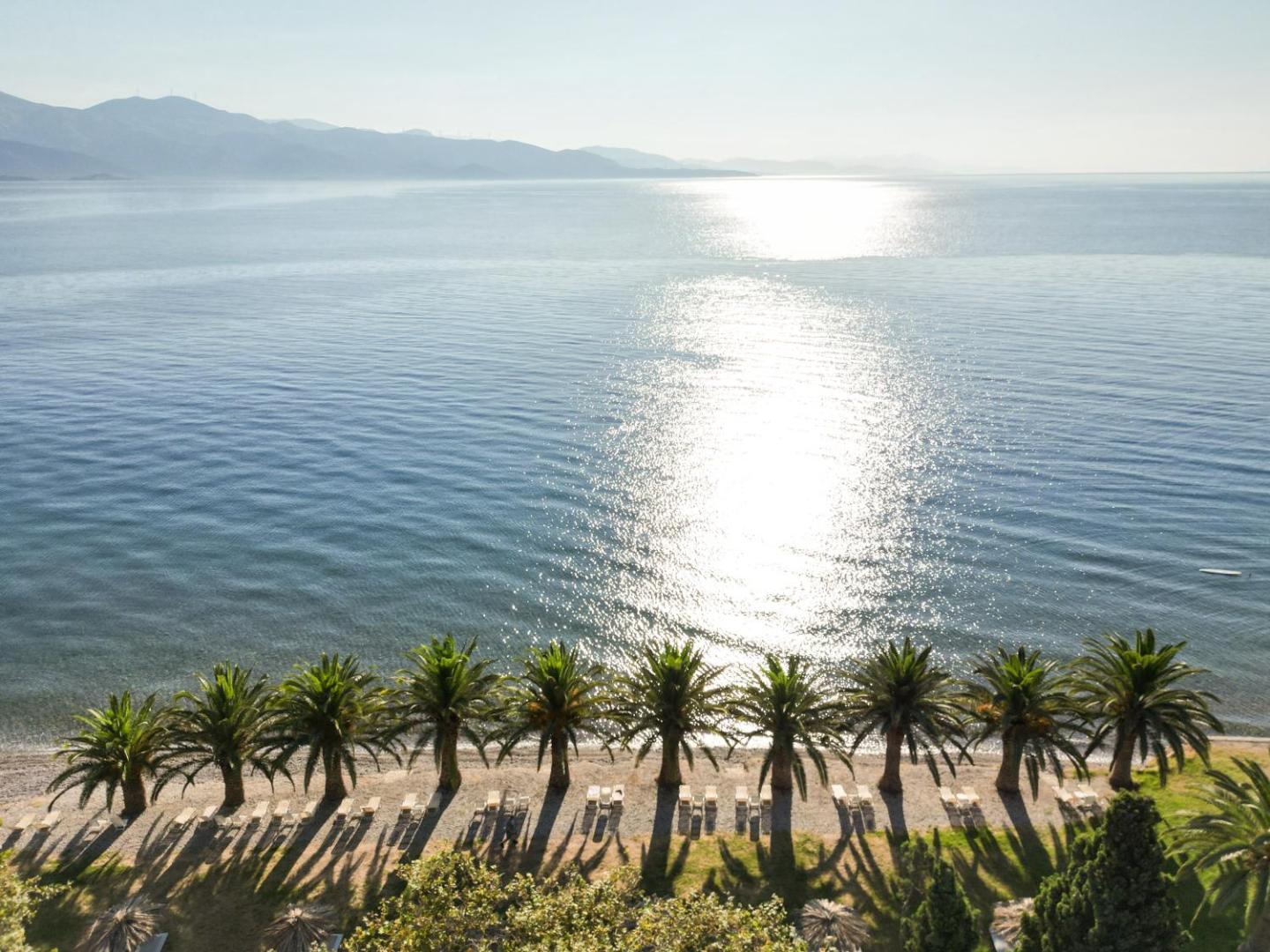 Aerofoto skats uz Long Beach Resort pludmales līniju ar palmu rindu, sauļošanās krēsliem un mirdzošu jūras ūdeni saulē.