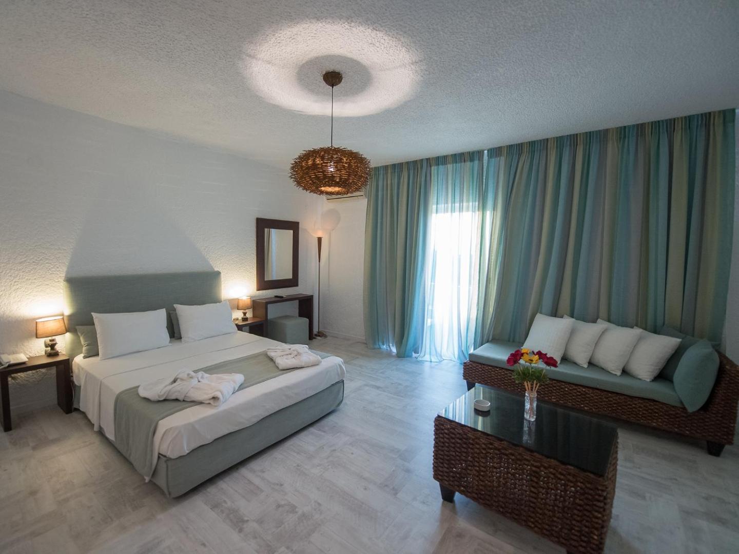 Long Beach Resort plašs viesnīcas numurs ar divguļamo gultu, atpūtas zonu un pītiem dīvāniem gaišos toņos