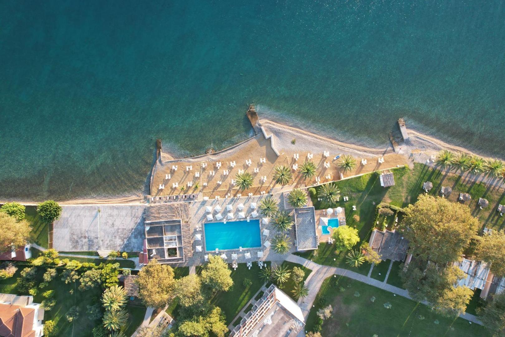 Long Beach Resort skats no putna lidojuma uz āra baseinu, pludmali un koptu dārzu Grieķijā — atpūtas zona ar saulessargiem