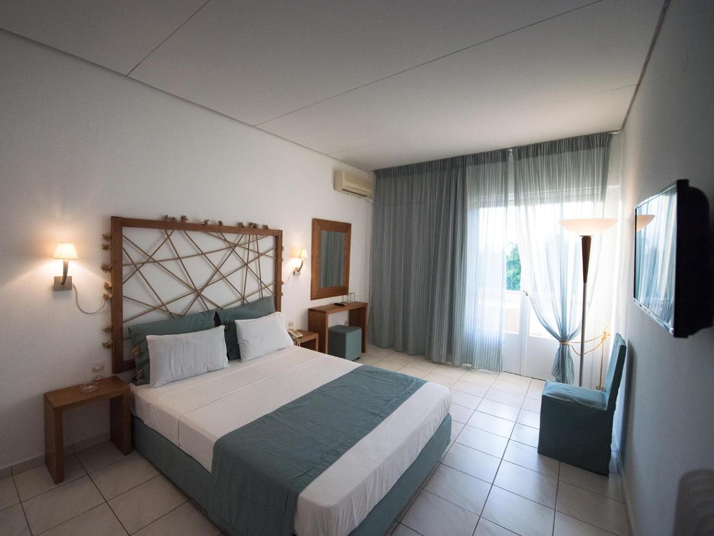 Viesnīcas Long Beach Resort numurs ar dekoratīvu koka galvgali, tualetes galdiņu un izeju uz balkonu