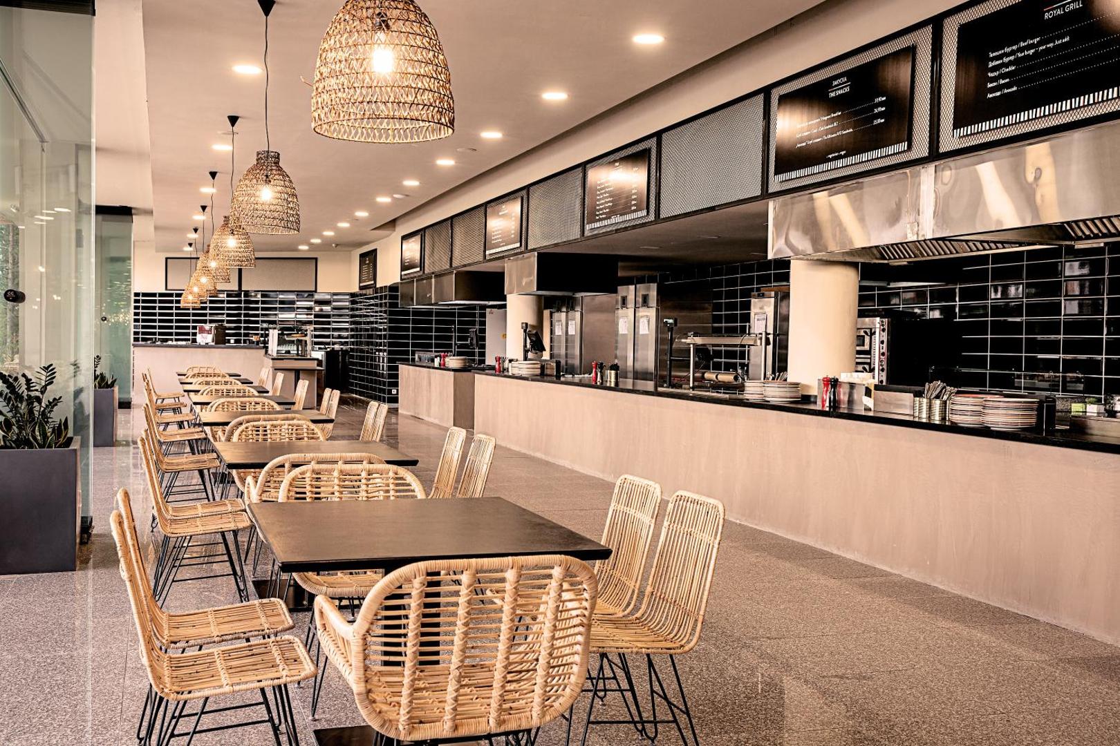 Sunny Beach Club modernā restorāna interjers ar atvērto virtuvi, pītiem krēsliem un stilīgiem gaismas ķermeņiem.