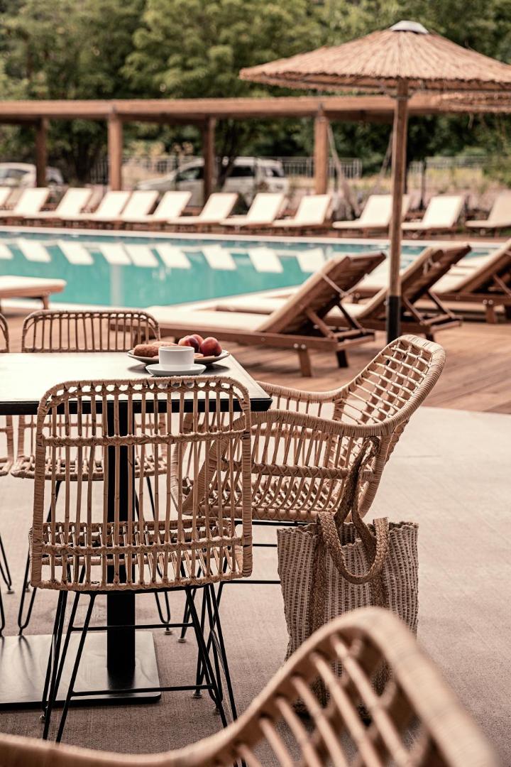Sunny Beach Club āra terase ar pītiem krēsliem pie baseina Saulainajā krastā, Bulgārijā – atpūtas zona ar saulessargiem un kafijas galdiņu.
