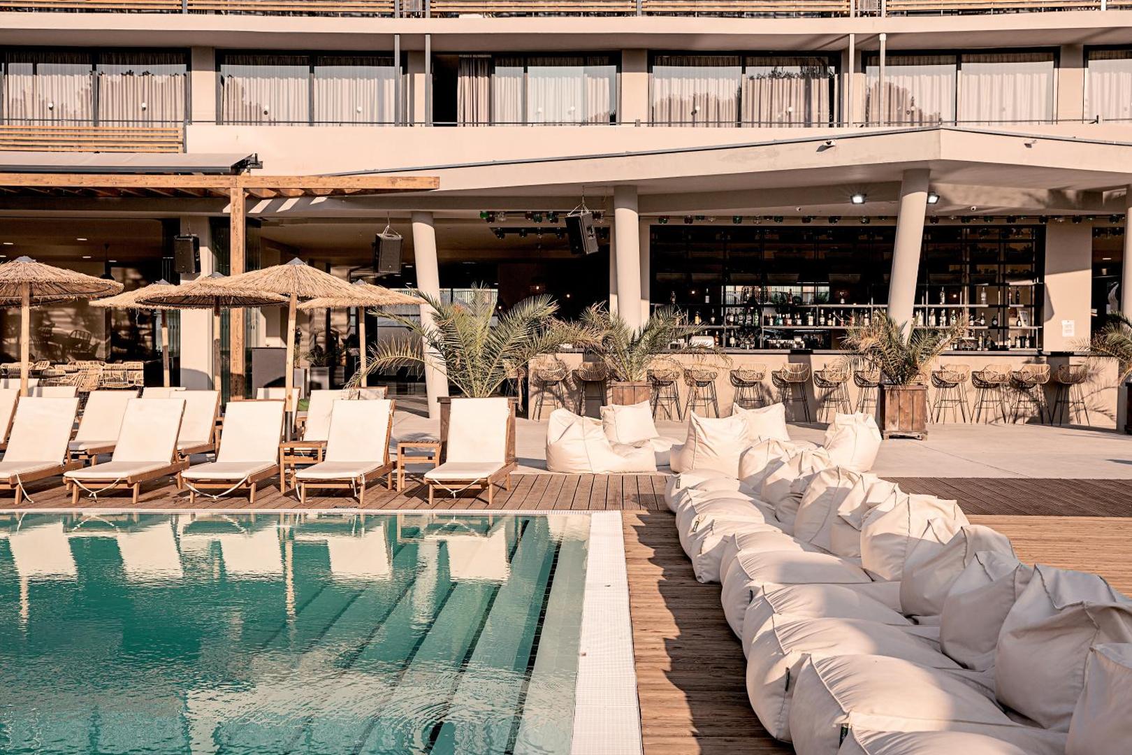 Sunny Beach Club āra bārs pie baseina ar mīkstiem sēžammaisiem un modernu atpūtas zonu viesnīcas teritorijā.