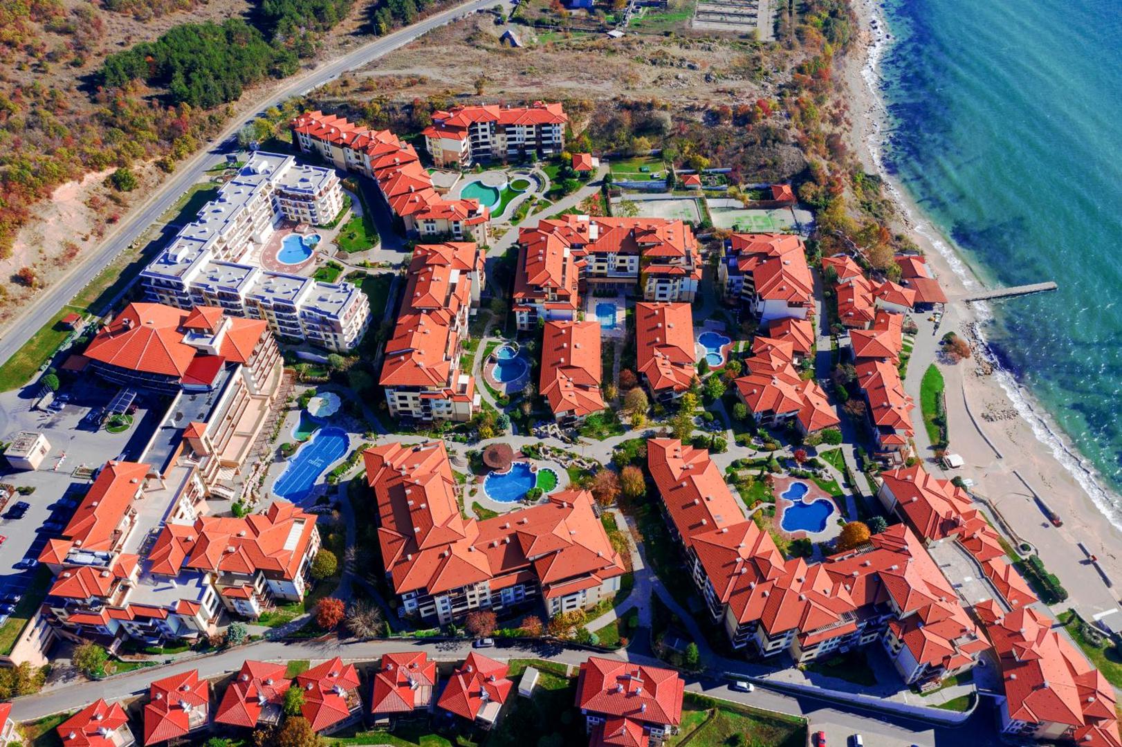 Garden Of Eden kūrorta panorāmas skats rudenī — viesnīcas ēkas ar sarkaniem dakstiņu jumtiem un baseiniem piekrastē