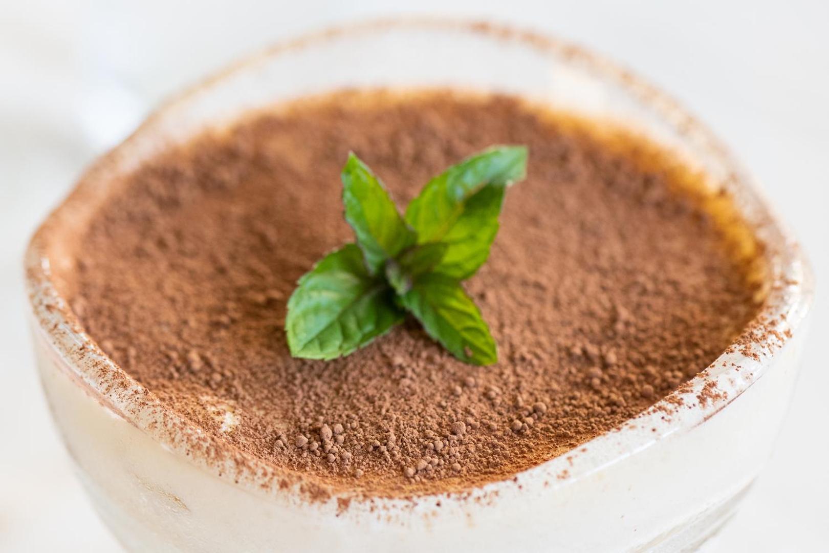 Klasisks tiramisu deserts ar kakao pulveri un svaigu piparmētru Garden Of Eden viesnīcas restorānā Bulgārijas piekrastē