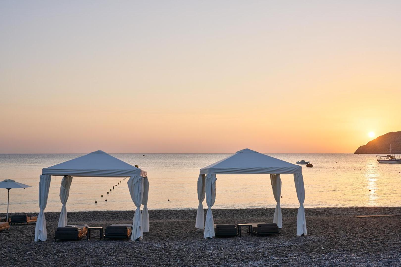 Lindos Grand Resort & Spa pludmales teltis jeb lapenes saulrieta gaismā Rodas piekrastē — romantiska atpūtas zona pie pašas jūras