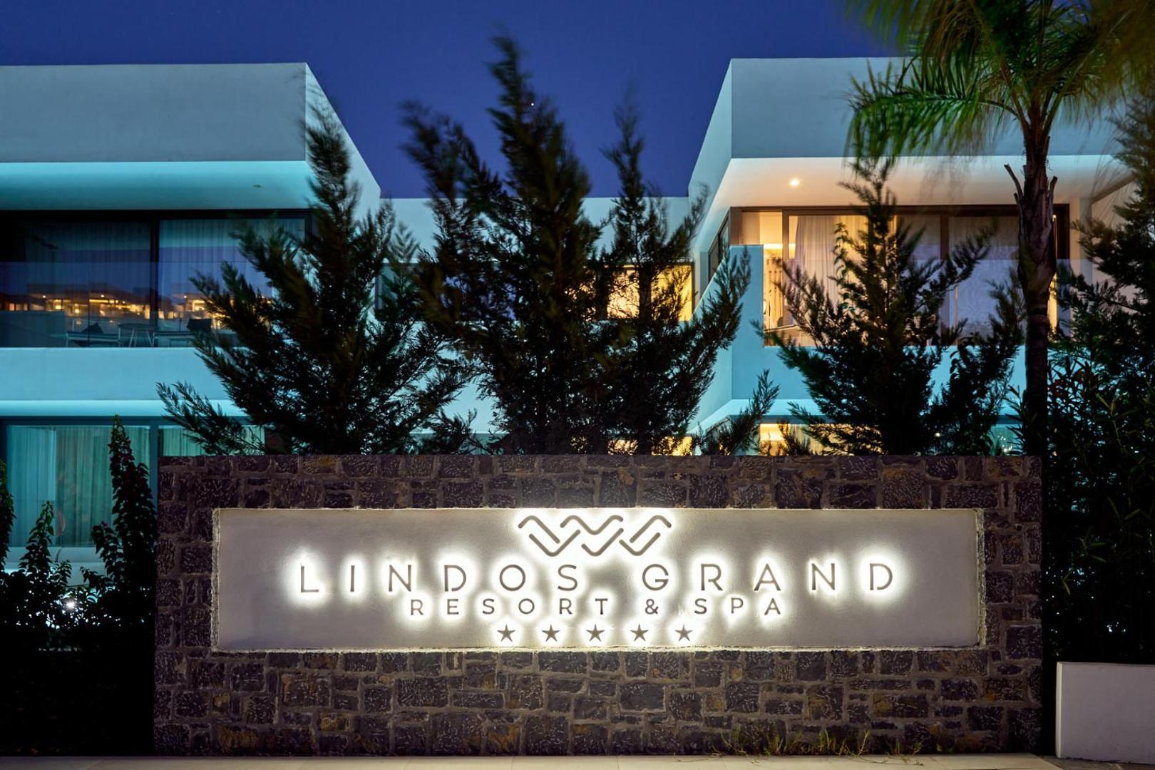 Lindos Grand Resort & Spa izgaismota ieejas zīme un 5* viesnīcas fasāde vakara stundās Rodas salā