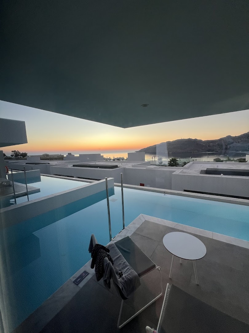 Skats no Lindos Grand Resort & Spa numura ar tiešu piekļuvi baseinam saulrieta laikā virs līča