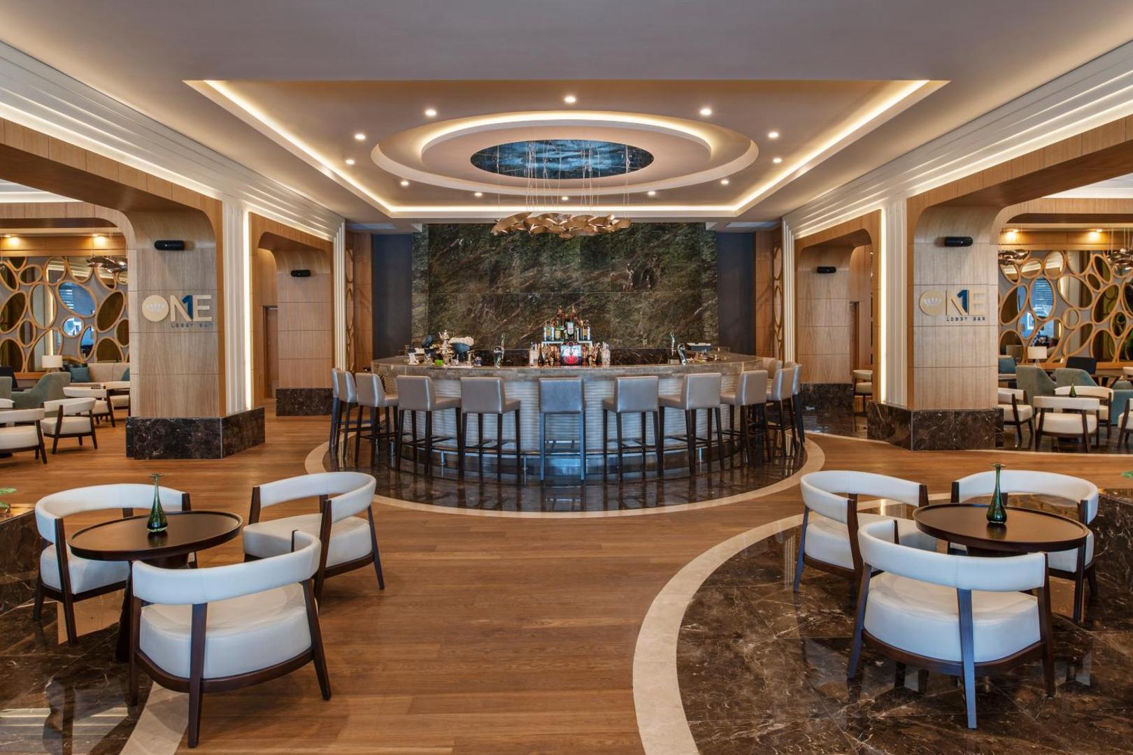 Regnum Carya modernais Lobby Bar ar apļveida leti, stilīgiem krēsliem un greznu griestu apgaismojumu viesnīcas galvenajā ēkā