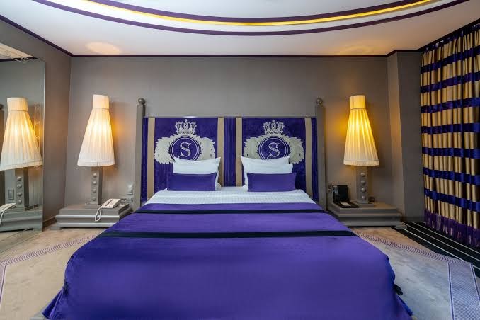 Selectum Luxury Resort numurs ar karaliski zilu gultas pārklāju, greznu galvgali un dizaina lampām siltā apgaismojumā.