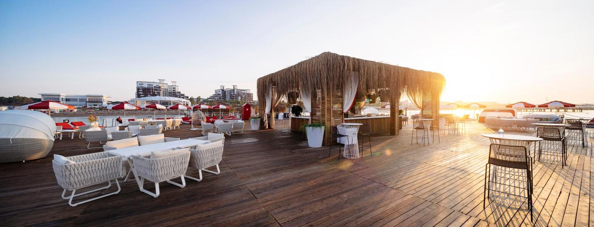 Selectum Luxury Resort koka terase ar pludmales bāru saulrietā Belekā — atpūtas zona ar dīvāniem un skatu uz jūru