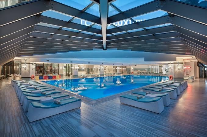 Selectum Luxury Resort moderns iekštelpu baseins ar stikla jumtu un ergonomiskiem zviļņiem — plaša spa un relaksācijas zona