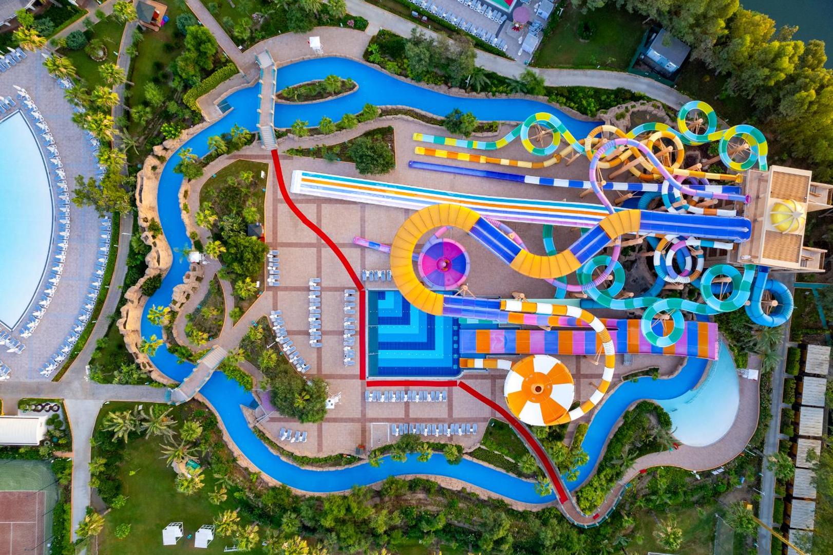 Delphin Be Grand Resort akvaparks no putna lidojuma — krāsaini ūdens slidkalniņi, baseini un atpūtas zona Antalijas piekrastē, Turcijā