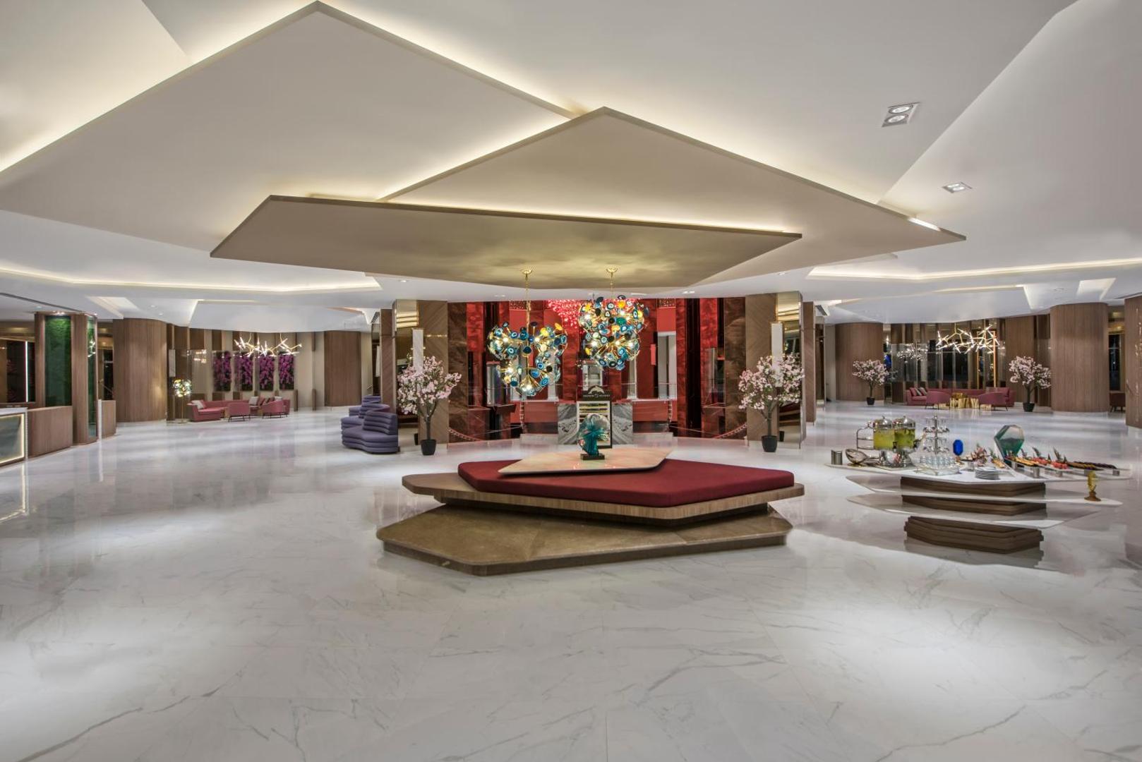 Delphin Be Grand Resort plašais un modernais vestibils ar marmora grīdām, dizaina apgaismojumu un atpūtas zonām viesu uzņemšanai.