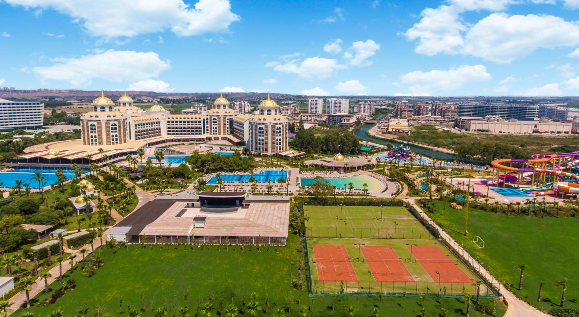Delphin Be Grand Resort teritorija no augšas — redzami tenisa korti, akvaparks, baseini un plašas zaļās zonas Antalijā