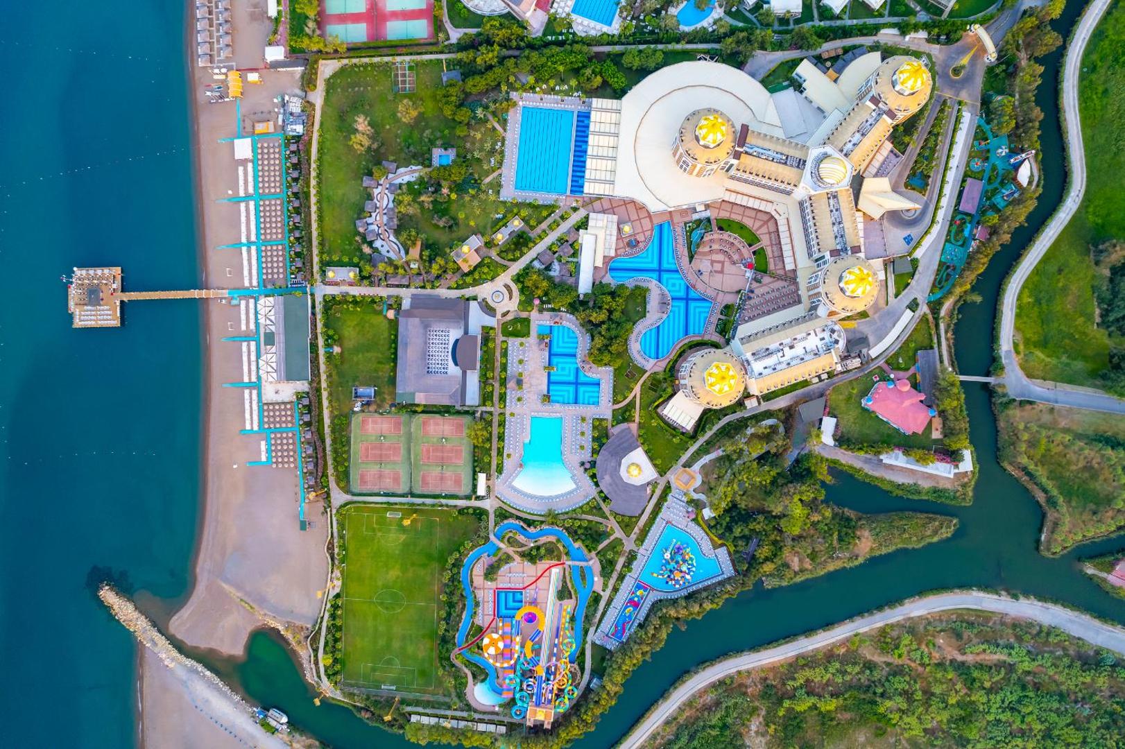 Delphin Be Grand Resort aerofoto skats — viesnīcas pludmale, piestātne, futbola laukums un baseinu komplekss pie Vidusjūras