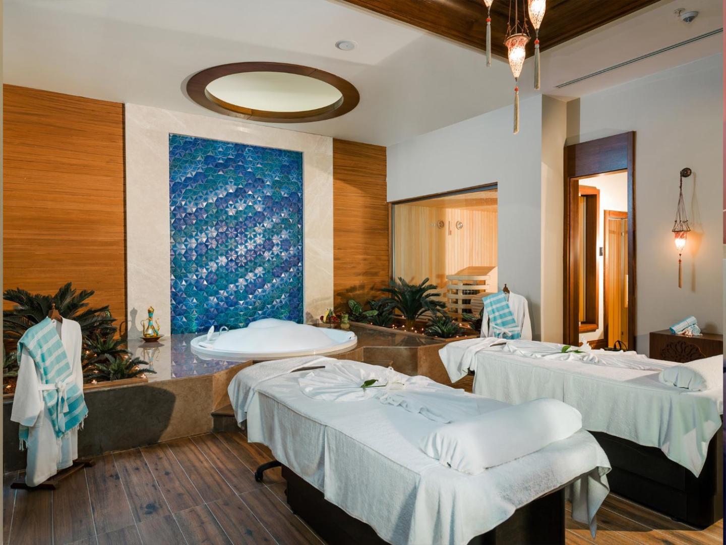 Gural Premier Belek spa centra procedūru telpa ar masāžas galdiem, džakuzi un zilu mozaīkas sienu Belekā