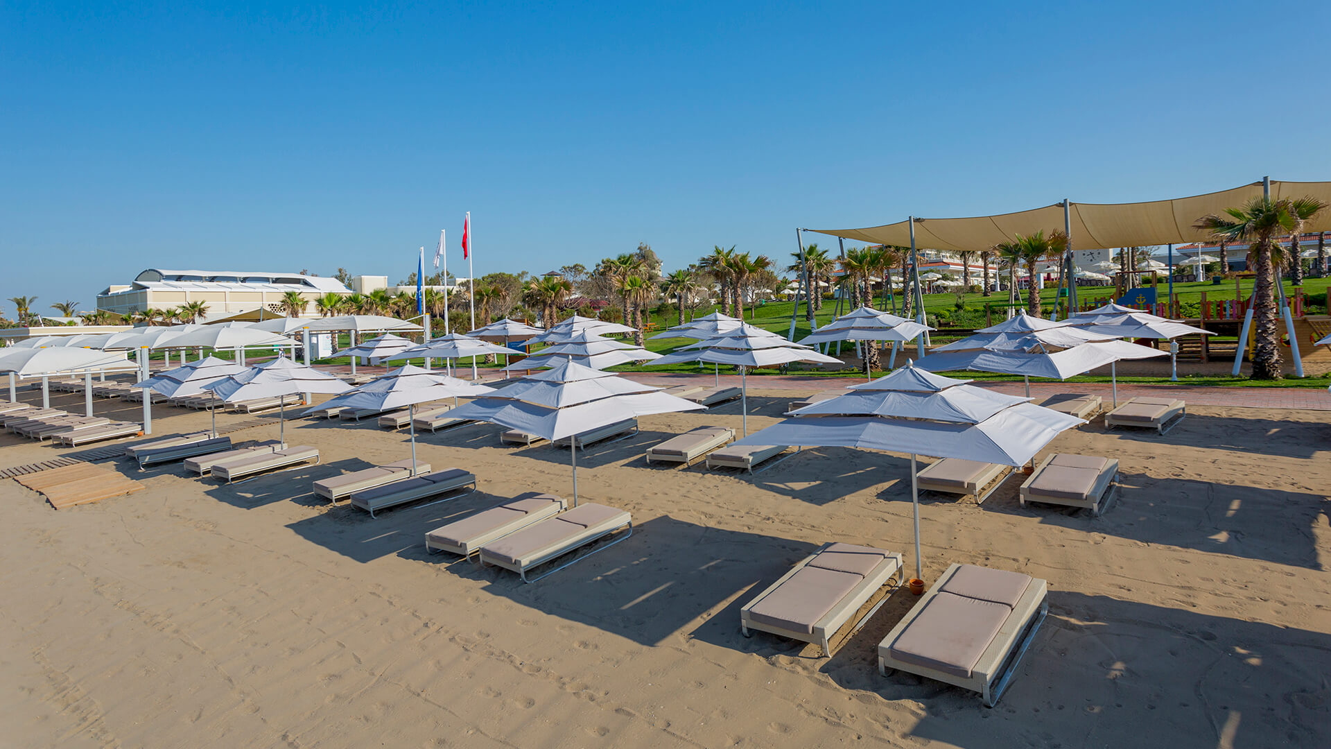 Gural Premier Belek plašā smilšu pludmale ar daudziem saulessargiem un zviļņiem — sakopta piekrastes zona Belekas reģionā Turcijā