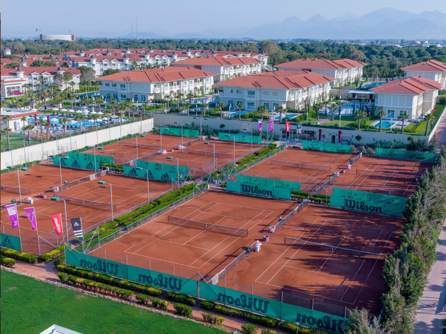 Gural Premier Belek aerofoto skats uz plašajiem tenisa kortiem ar māla segumu un kūrorta villām Belekā, Turcijā