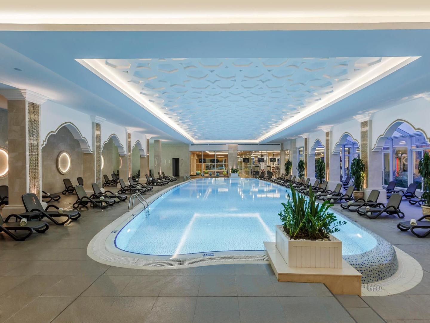 Gural Premier Belek plašais iekštelpu baseins ar dekoratīviem griestiem, arkām un atpūtas krēsliem spa zonā