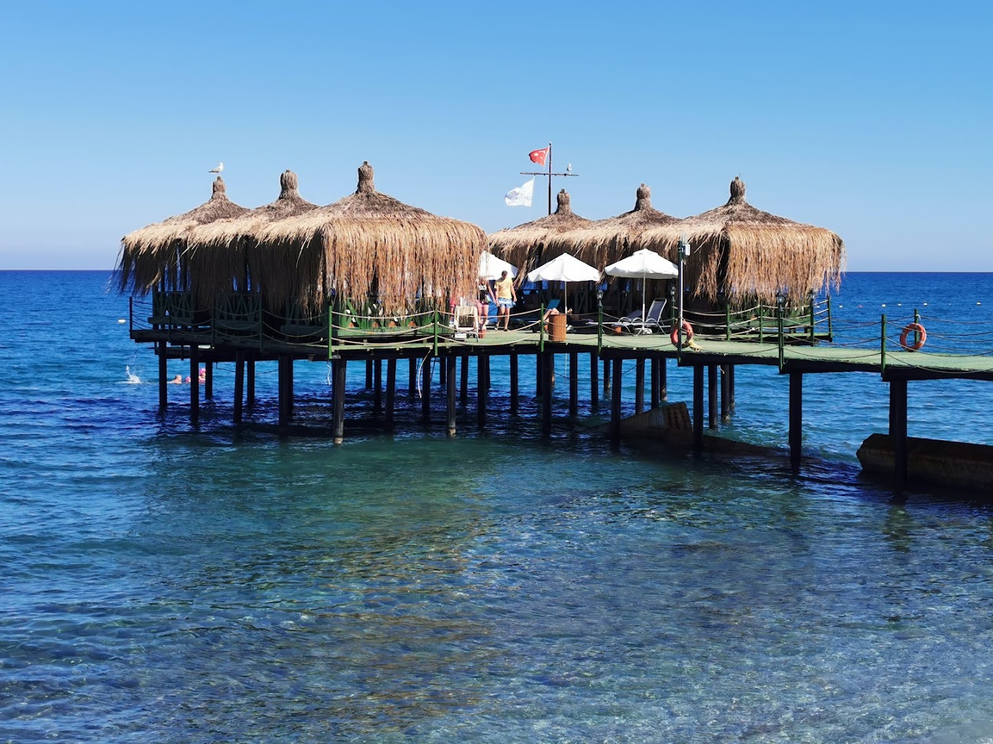 Crystal Flora Beach Resort koka piestātne ar bungalo tipa atpūtas vietām virs dzidrā Vidusjūras ūdens Kemeras reģionā.
