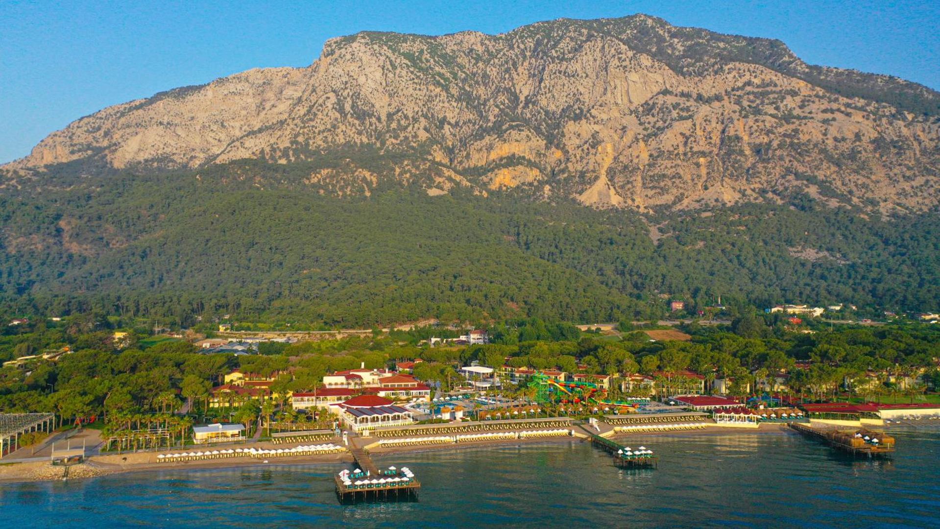 Crystal Flora Beach Resort panorāmas skats no putna lidojuma Beldibi reģionā, Turcijā — viesnīcas teritorija pie jūras kalnu pakājē