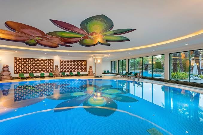 IC Hotels Green Palace iekštelpu baseins ar dekoratīviem ziedu motīviem uz griestiem un grīdas spa centrā Kundu reģionā