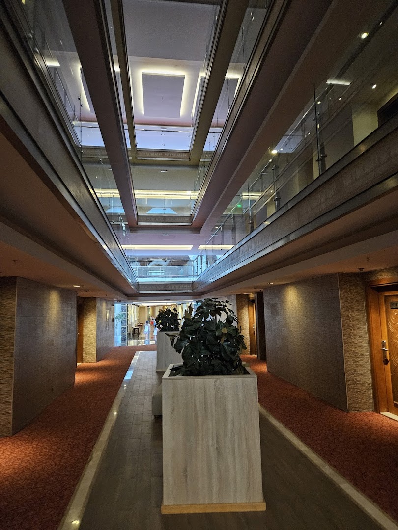 Crystal Prestige Elite viesnīcas iekšējais gaitenis ar paklāju, dekoratīviem augiem un skatu uz vairākiem stāviem caur atvērtu ātriju