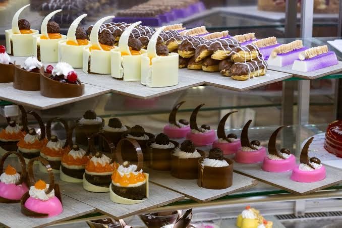 Juju Premier Palace konditorejas izstrādājumu un desertu izlase viesnīcas restorānā — krāsainas kūkas, eklēri un smalki saldumi