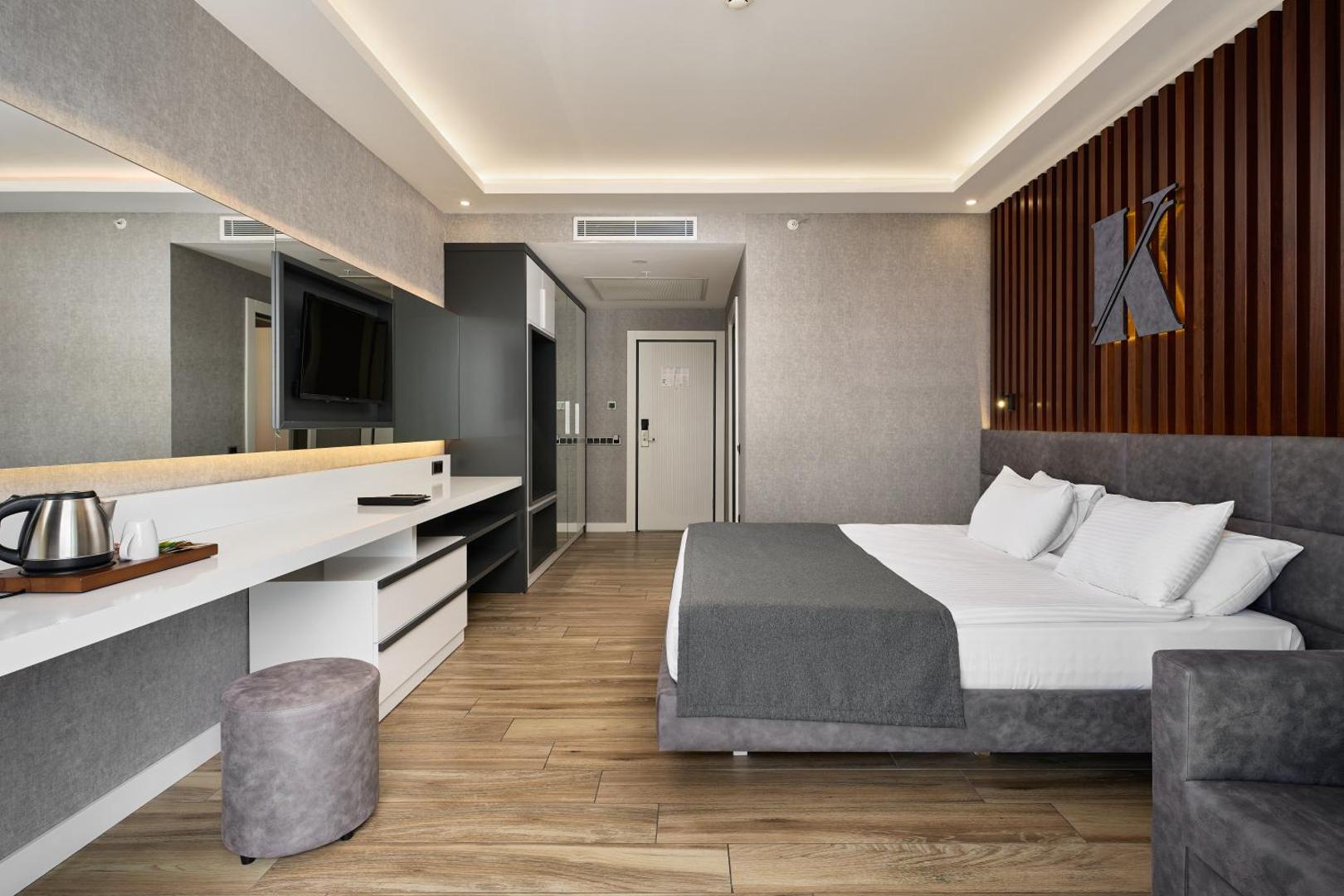 Kaila Beach Hotel moderns numurs ar divguļamo gultu, koka apdari, lielu spoguli un gaišu interjeru Alanjas kūrortā