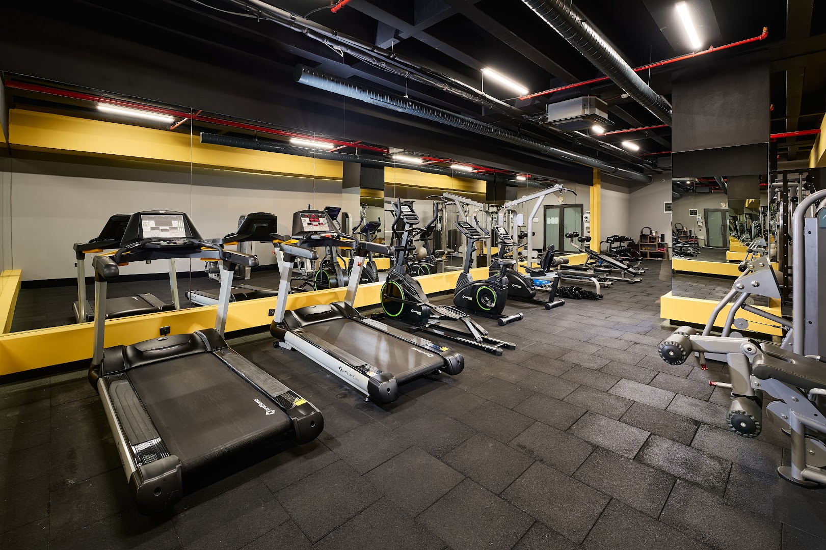 Kaila Beach Hotel modernais fitness centrs ar skrejceļiem un trenažieriem — plaša zāle ar spoguļiem un profesionālu aprīkojumu