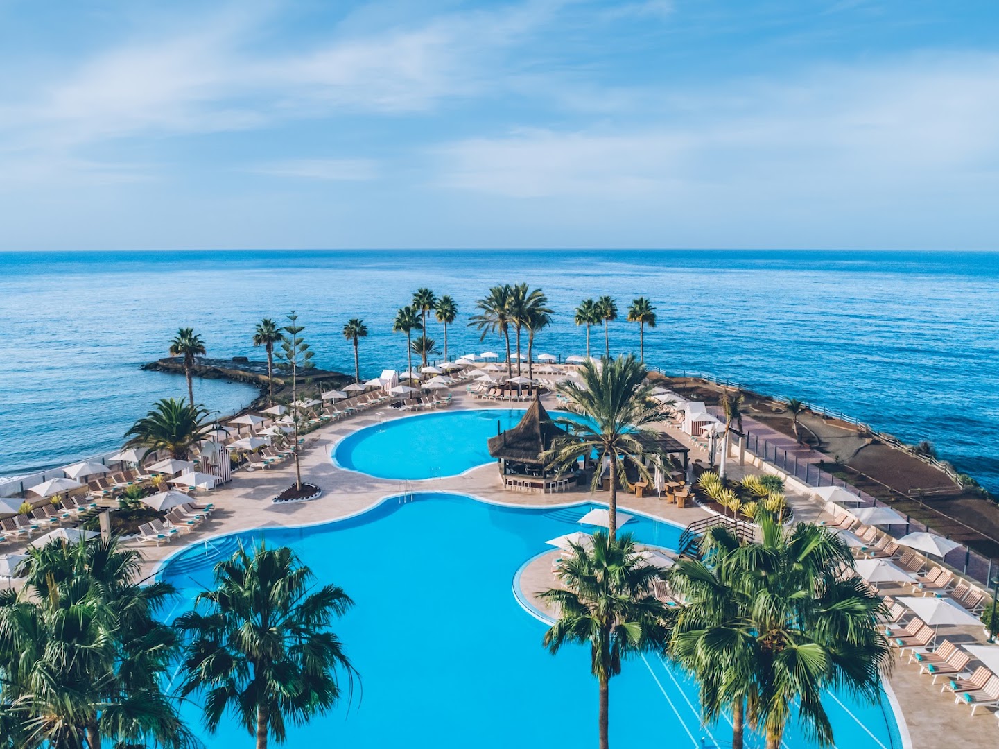 Aerofoto skats uz Iberostar Selection Anthelia baseiniem un terasi pie okeāna Tenerifē — izteiksmīga piekrastes līnija un kūrorta infrastruktūra.