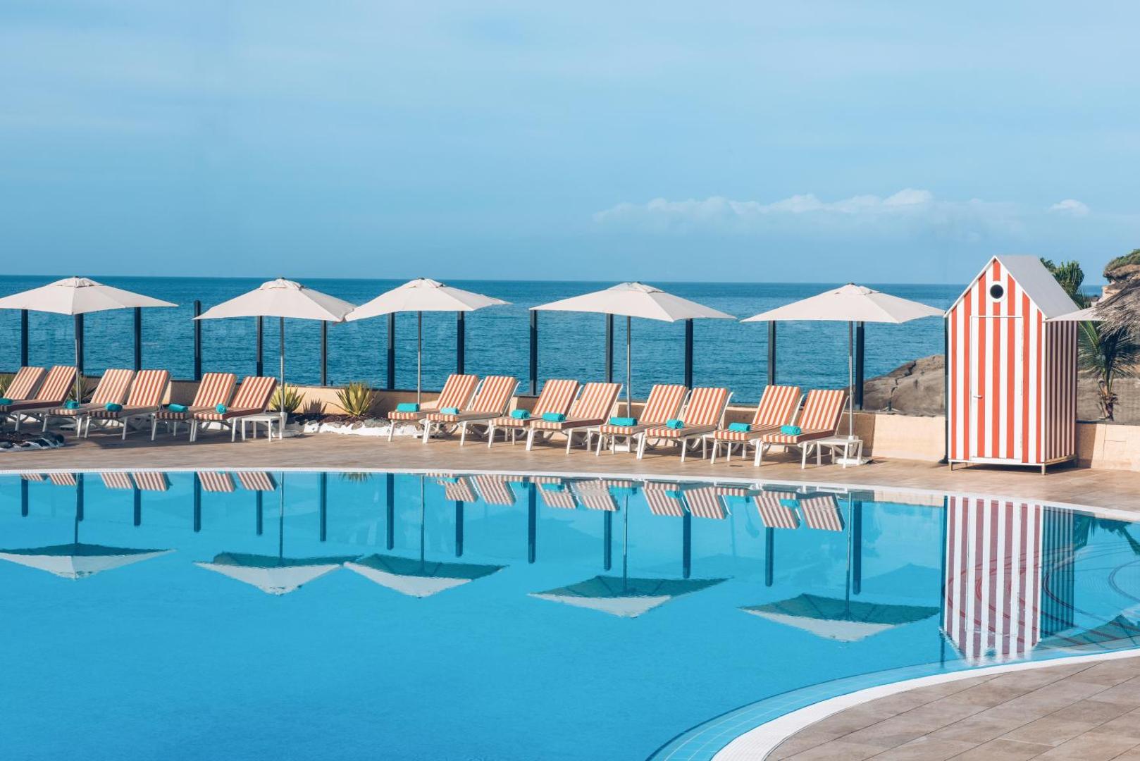 Atpūtas krēsli ar saulessargiem pie Iberostar Selection Anthelia baseina ar skatu uz Atlantijas okeānu.