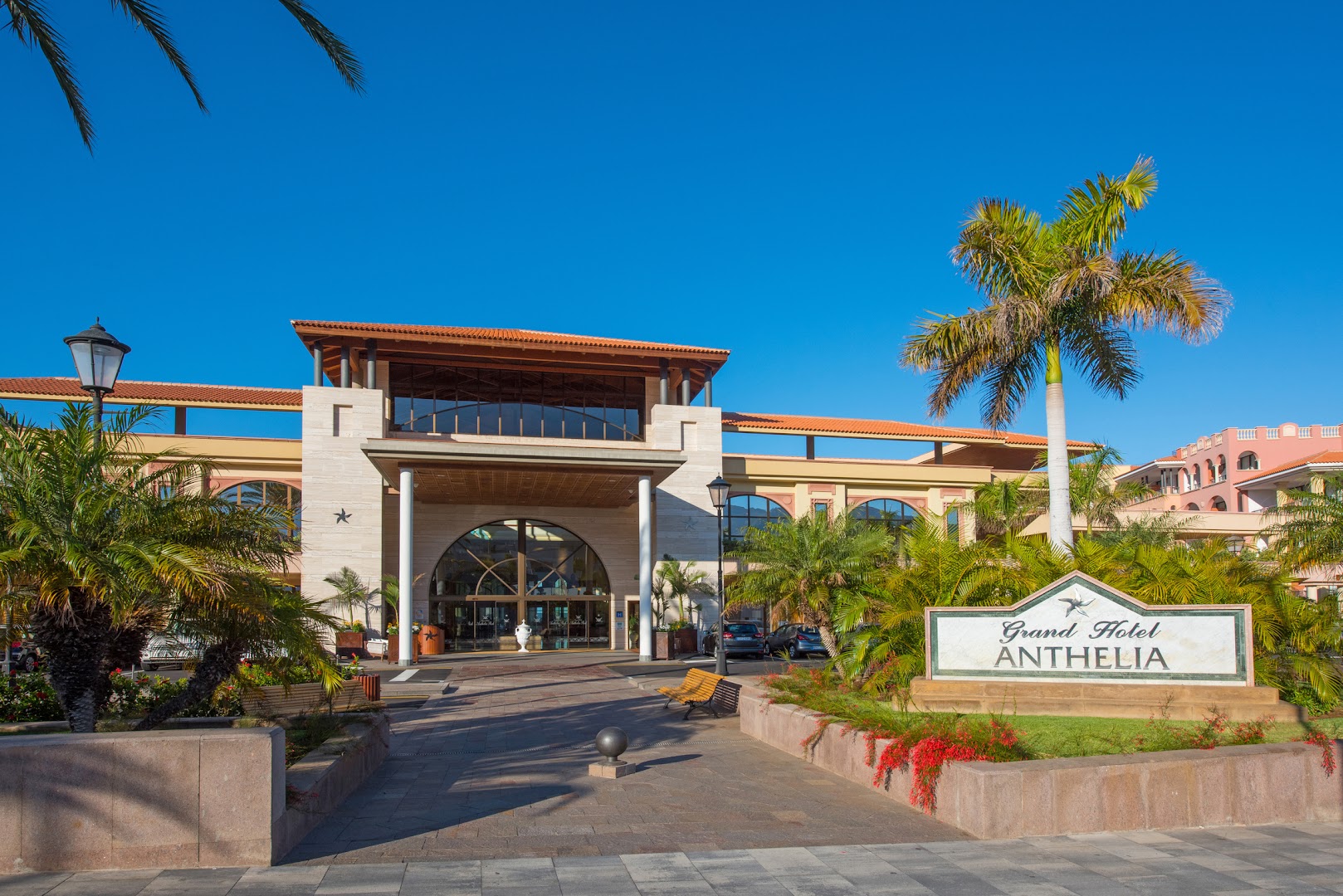 Iberostar Selection Anthelia galvenā ieeja ar viesnīcas nosaukumu, palmām un modernu arhitektūru saulainā dienā Tenerifē
