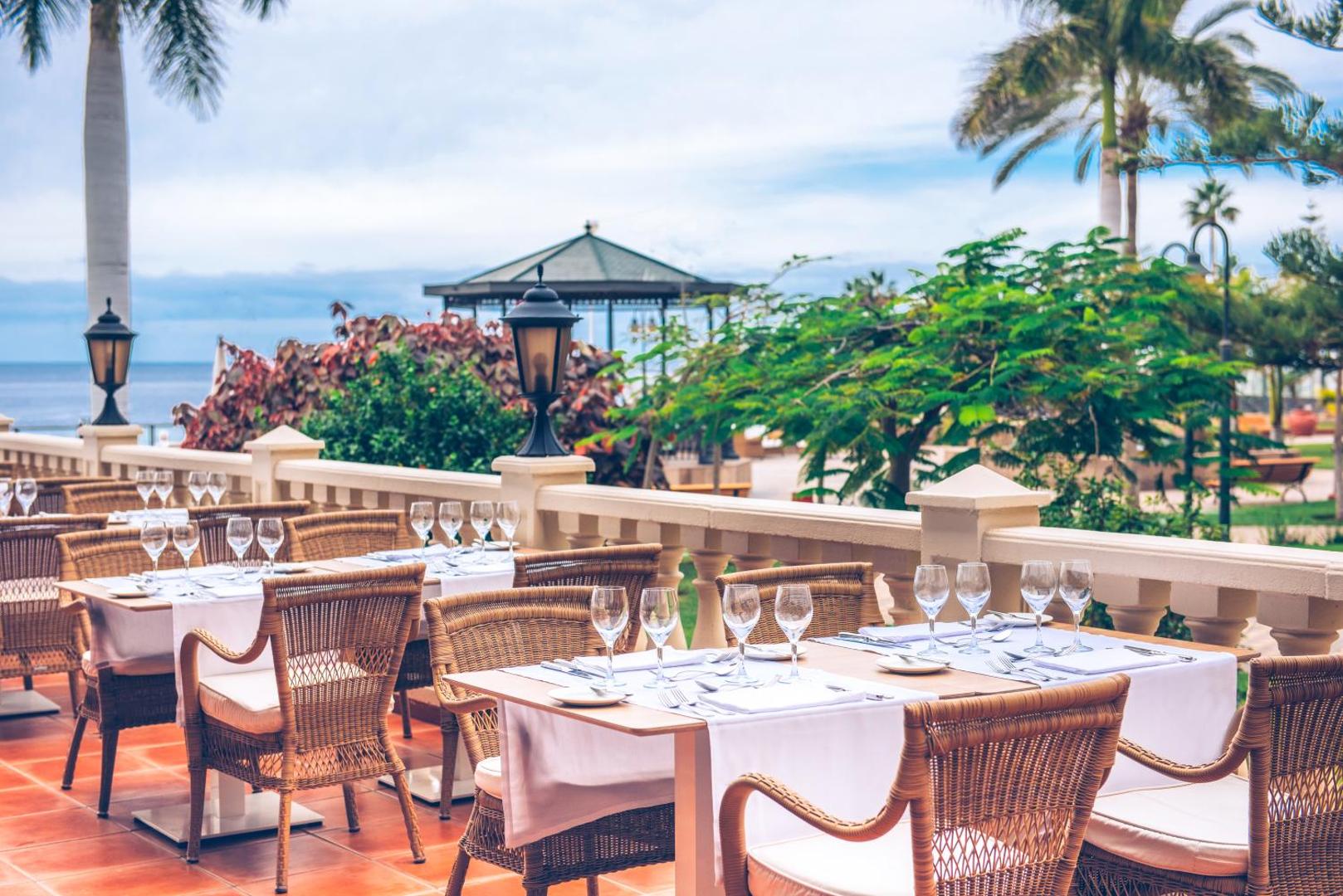 Iberostar Selection Anthelia restorāna āra terase ar klātiem galdiem, pītiem krēsliem un skatu uz dārzu un okeānu Tenerifē
