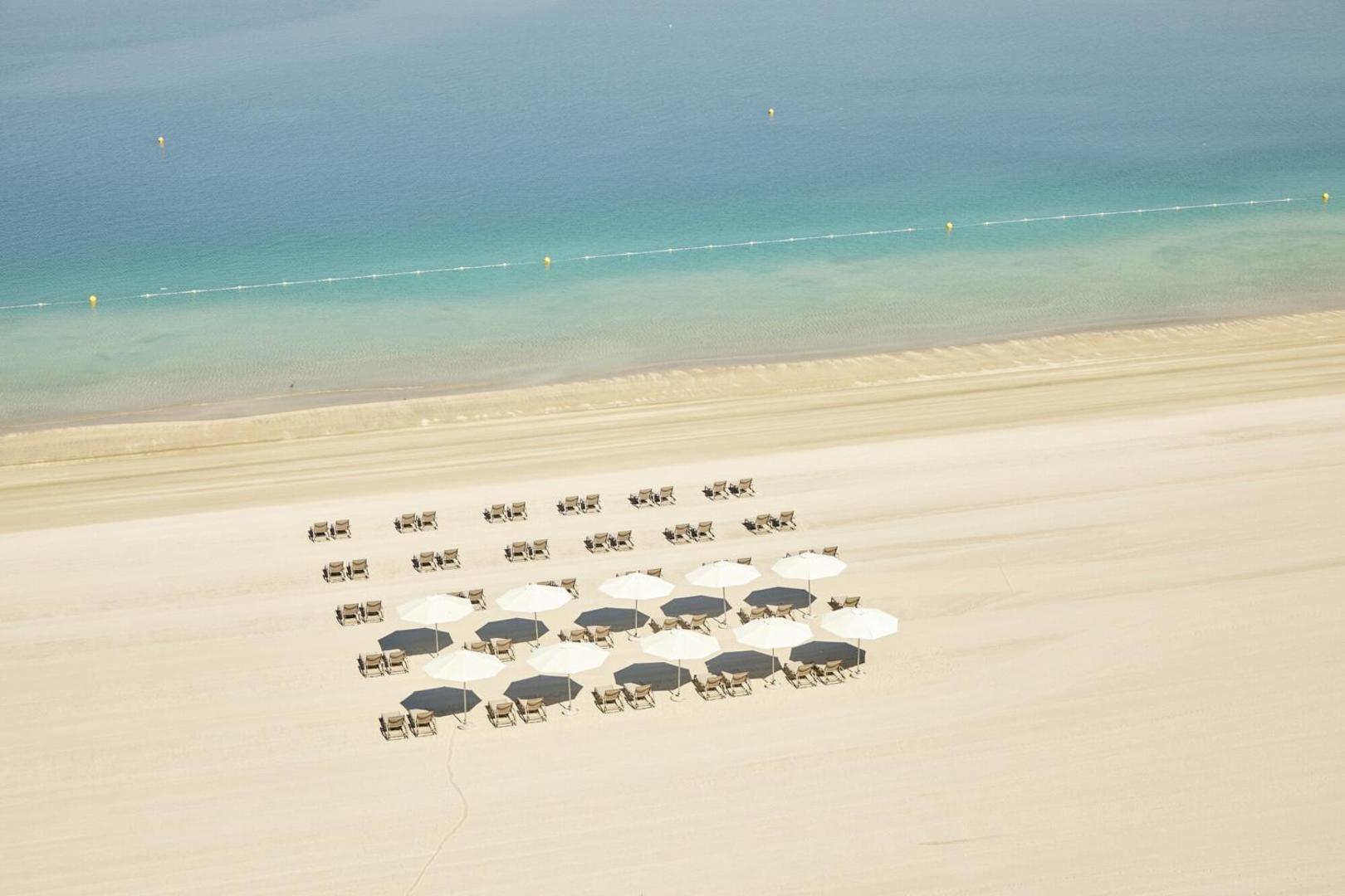Viesnīcas RIU Dubai privātā pludmale ar gaišām smiltīm, saulessargiem un sauļošanās krēsliem pie dzidri zilā Persijas līča ūdens