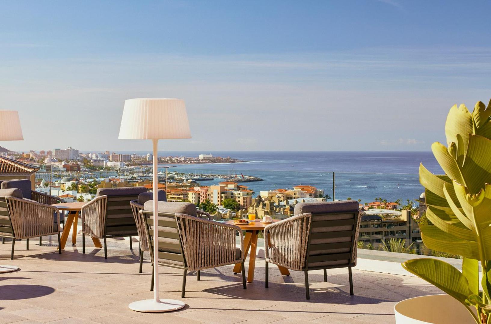 Meliá Jardines del Teide viesnīcas terase ar atpūtas krēsliem un skatu uz okeānu un pilsētu Tenerifē, Spānijā