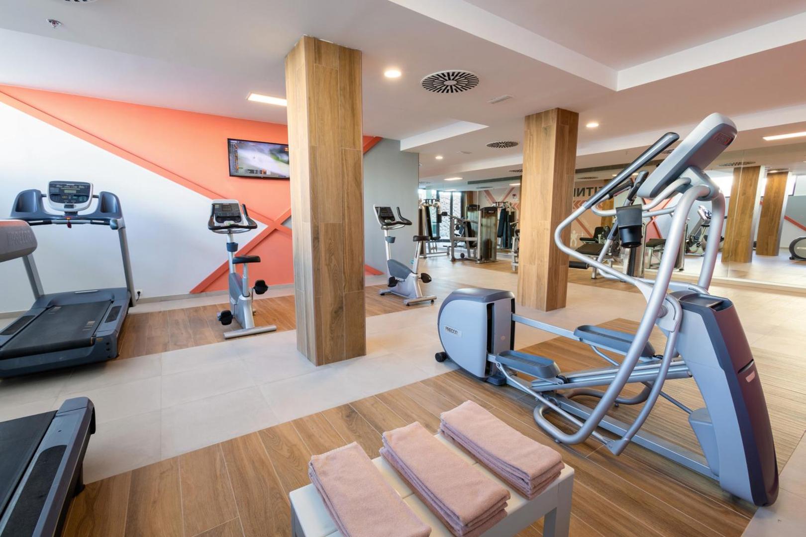 Riu Buena Vista fitnesa centrs ar moderniem trenažieriem, skrejceliņiem, velotrenažieriem un gaišu koka apdari sportiskām aktivitātēm