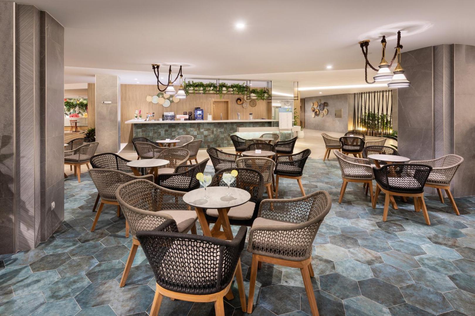 Riu Buena Vista lobby bārs ar stilīgiem pītiem krēsliem, zilganu flīžu grīdu, kokteiļiem uz galdiem un mājīgu apgaismojumu