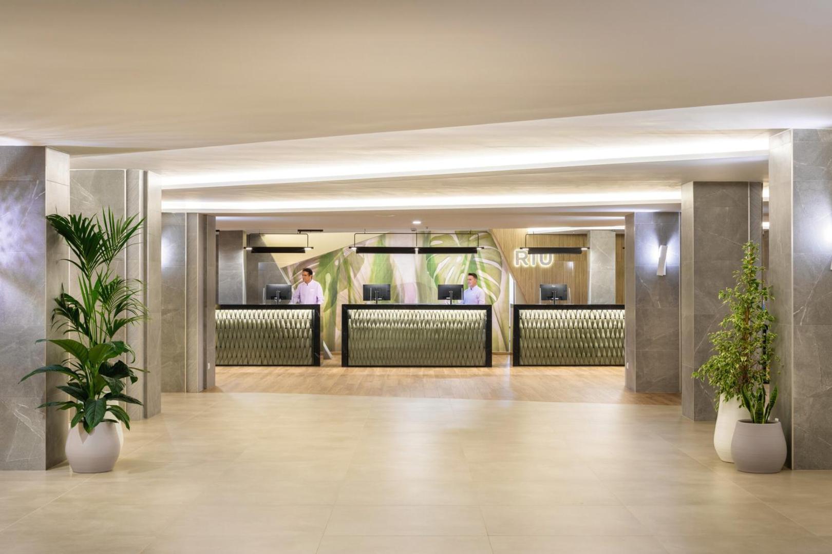 Riu Buena Vista viesnīcas recepcijas zona Tenerifē ar modernām reģistrācijas letēm, gaišu interjeru, dekoratīviem augiem un viesmīlīgu personālu