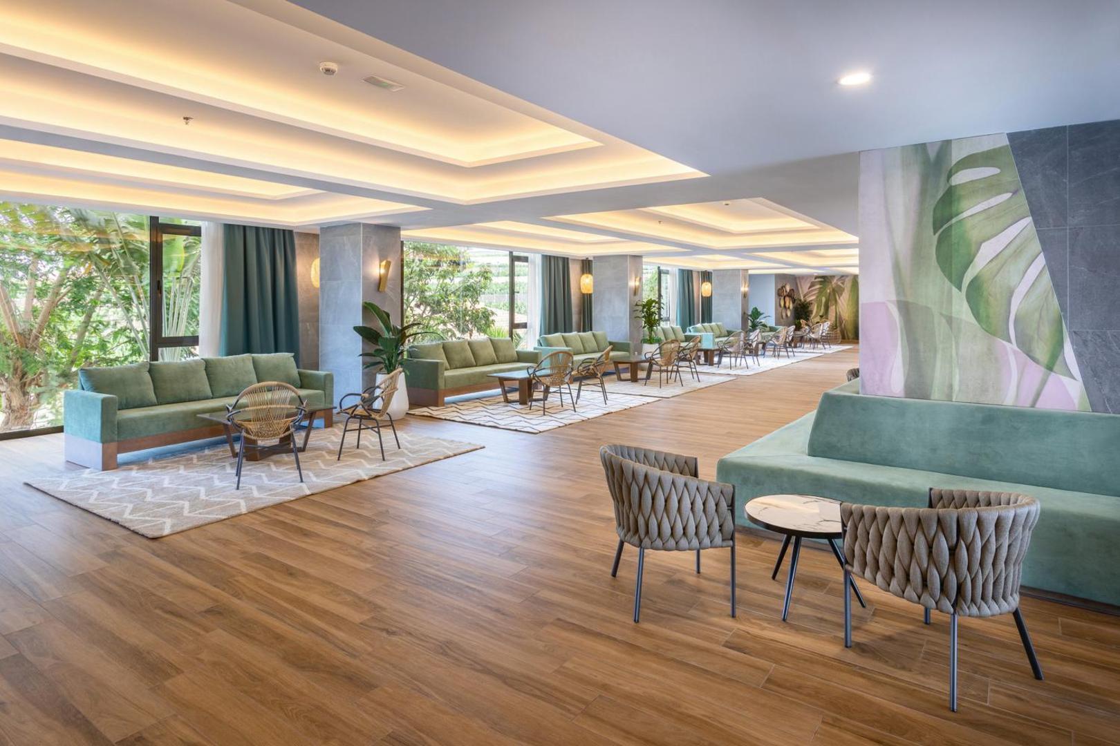Riu Buena Vista plašais lobby vestibils ar moderniem dīvāniem, koka grīdām un lieliem logiem uz dārzu