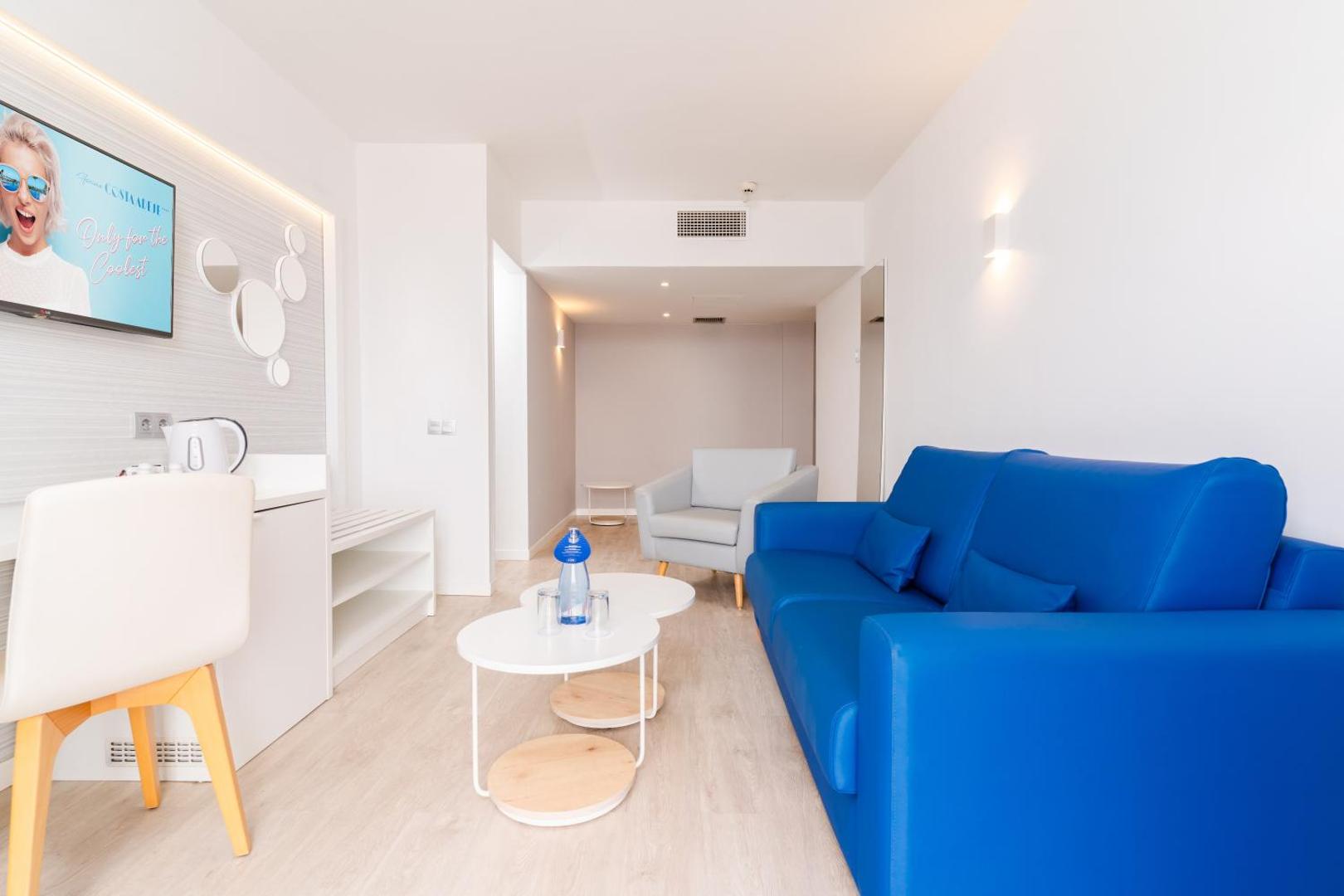 Hovima Cool Costa Adeje numura viesistabas zona ar zilu dīvānu, atpūtas krēslu un modernu interjeru Kanāriju salās