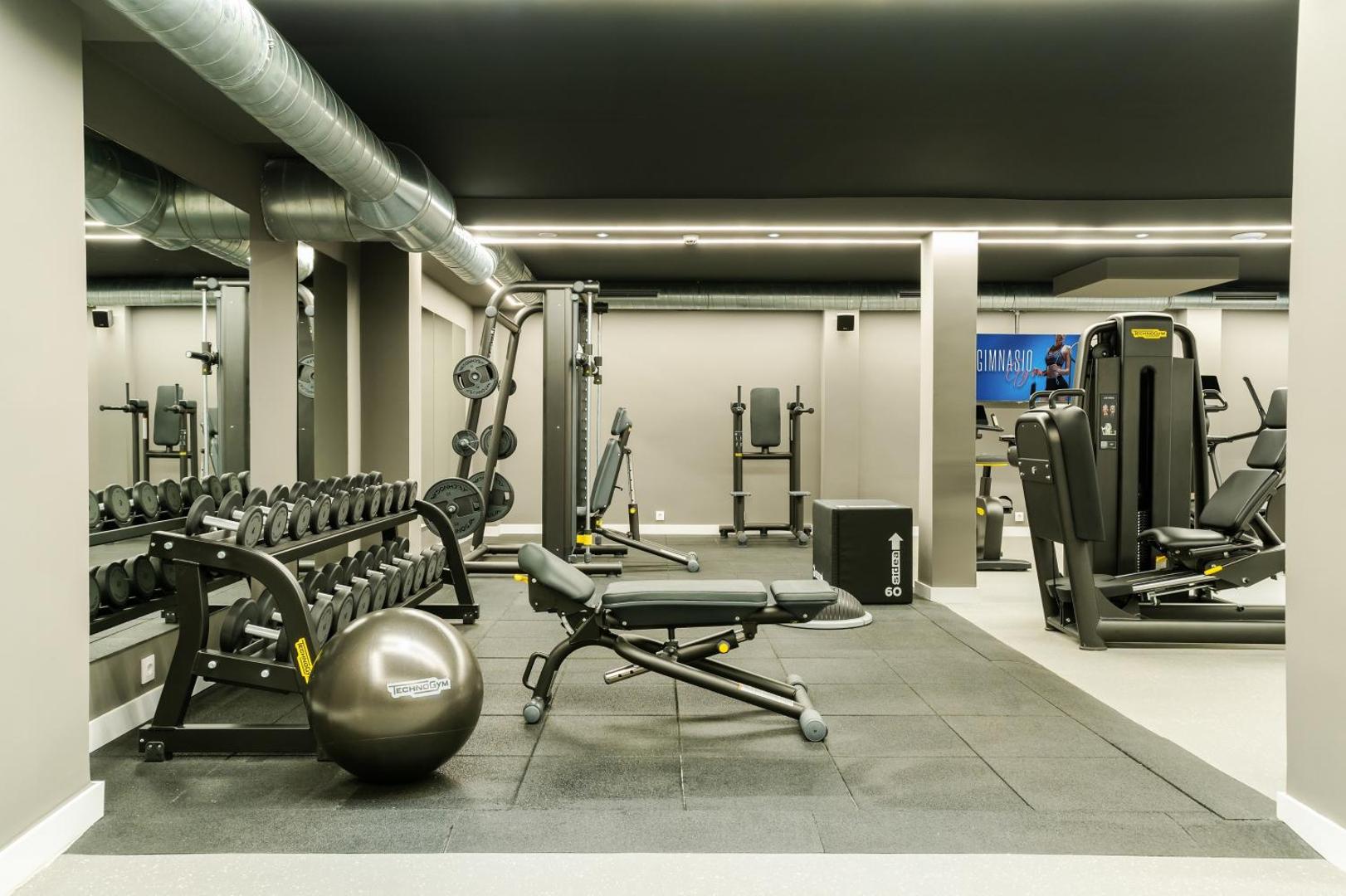Hovima Cool Costa Adeje moderna iekštelpu trenažieru zāle ar Technogym aprīkojumu, svariem un spoguļu sienu Tenerifes kūrortā.