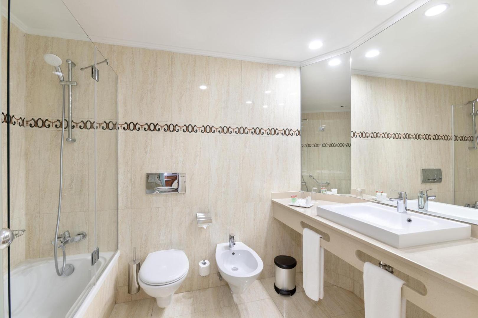 Alexandre Hotel Gala gaišs numura vannasistabas interjers ar vannu, dušu, lielu spoguli, tualeti un bide gaišos smilšu toņos