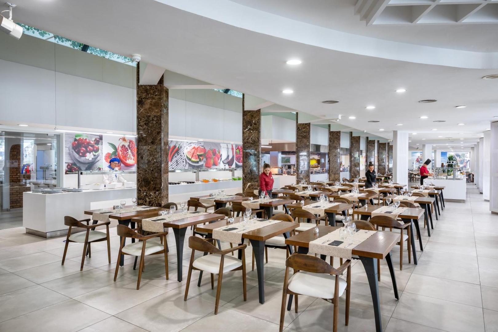 Alexandre Hotel Gala galvenais restorāns ar modernu interjeru, klātiem galdiem un bufetes zonu — plaša un gaiša ēdamzāle viesiem