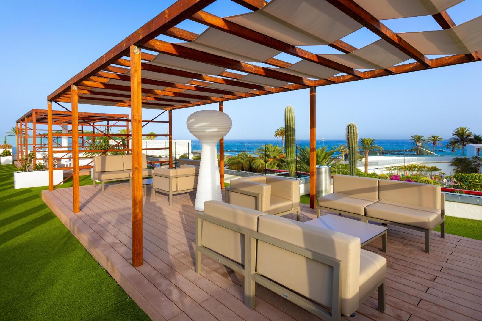 Alexandre Hotel Gala jumta terase ar mīkstajām mēbelēm zem koka nojumes un skatu uz piekrasti Tenerifē